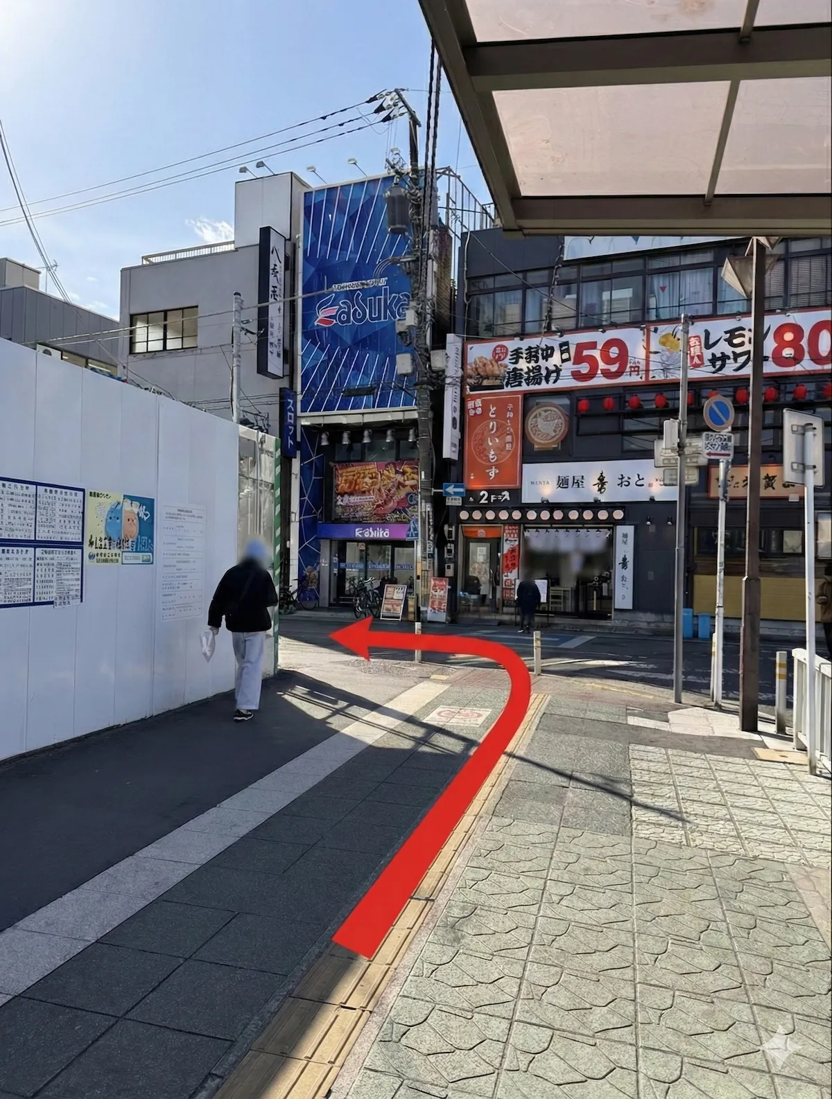 駅を出て左へ進み、バス乗り場を通り過ぎて左折、紅い矢印